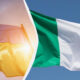 Two flags fluttering in the wind: a yellow flag with hints of red on the left and a green, white, and red flag on the right.