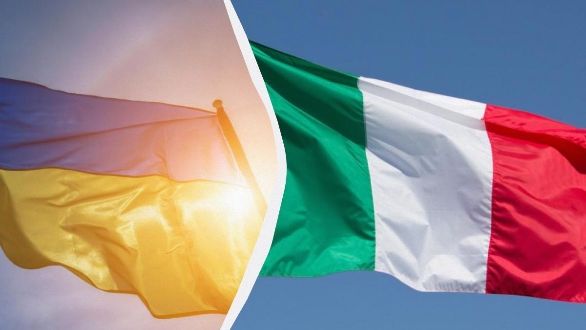 Two flags fluttering in the wind: a yellow flag with hints of red on the left and a green, white, and red flag on the right.