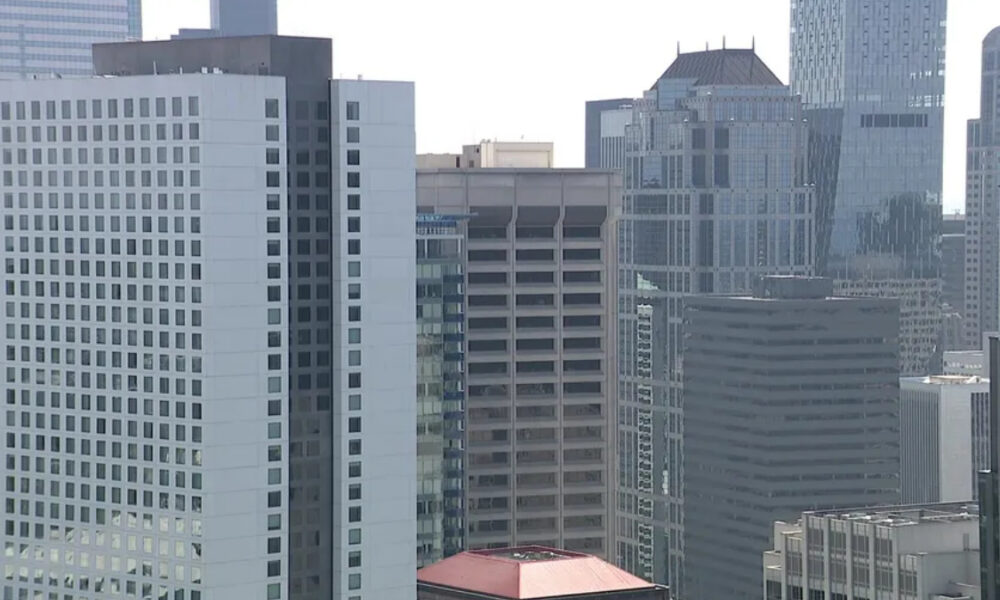 City skyline with tall modern office buildings and glass facades in a dense urban downtown area