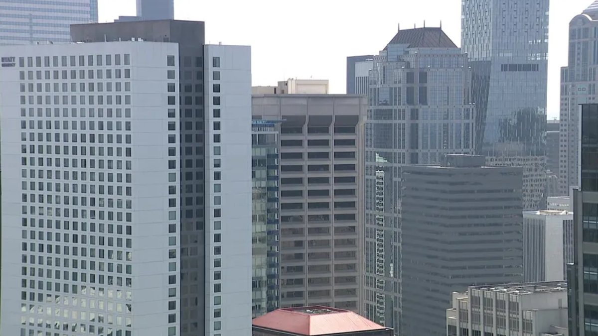 City skyline with tall modern office buildings and glass facades in a dense urban downtown area