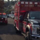 Front-right view of a red East Pierce Fire & Rescue ambulance with flashing lights, parked on a suburban street with other emergency vehicles in the background.