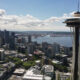 Seattle skyline with the Space Needle overlooking Puget Sound on a sunny day, city to the left and water to the right.