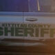 Side view of a Kittitas County Sheriff's patrol car with green SHERIFF lettering and a star badge on the door panel