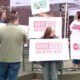 Group of people at an outdoor political rally holding signs reading 'Vote Yes on IP26-645'.