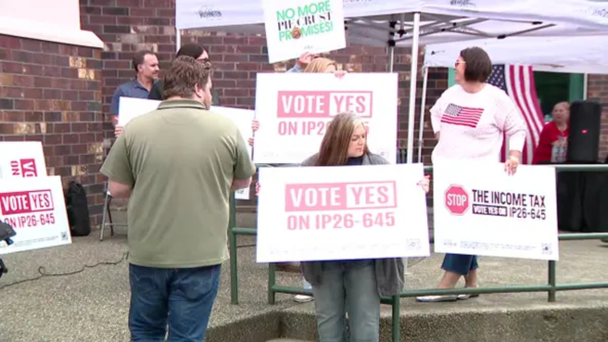 Group of people at an outdoor political rally holding signs reading 'Vote Yes on IP26-645'.