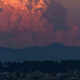 Seattle skyline at dusk with Space Needle against pink-orange clouds and distant hills, city lights below.