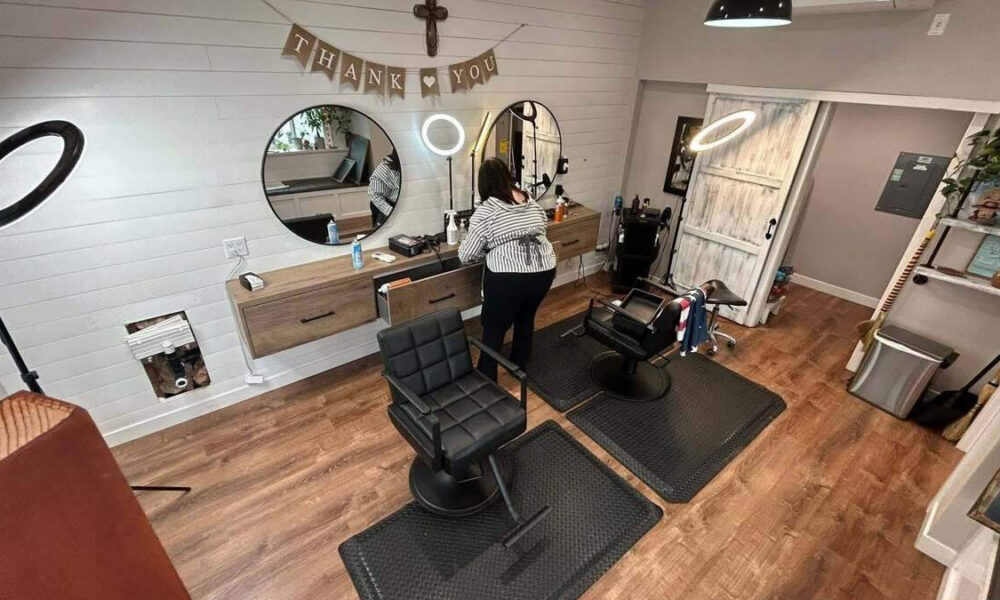 Cozy hair salon with two black barber chairs, round mirrors, and a 'Thank You' banner above the stations.
