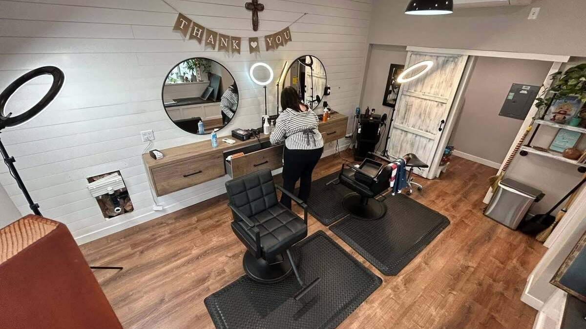 Cozy hair salon with two black barber chairs, round mirrors, and a 'Thank You' banner above the stations.