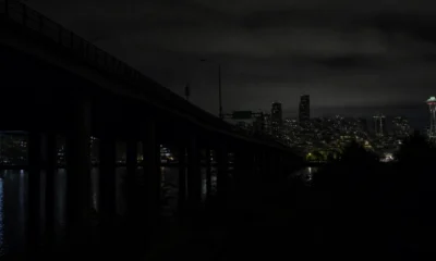 Nighttime city skyline with a bridge in the foreground and the illuminated Space Needle in Seattle.