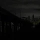 Nighttime city skyline with a bridge in the foreground and the illuminated Space Needle in Seattle.