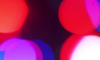 Abstract bokeh lights in red, pink, and purple against a dark background.