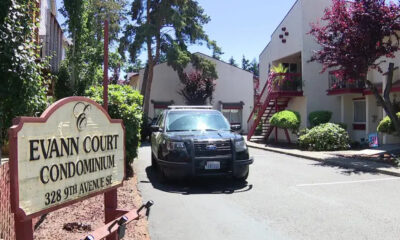 Sign reads Evann Court Condominium; a black SUV is parked in a driveway beside the red-stair apartment building and trees nearby.