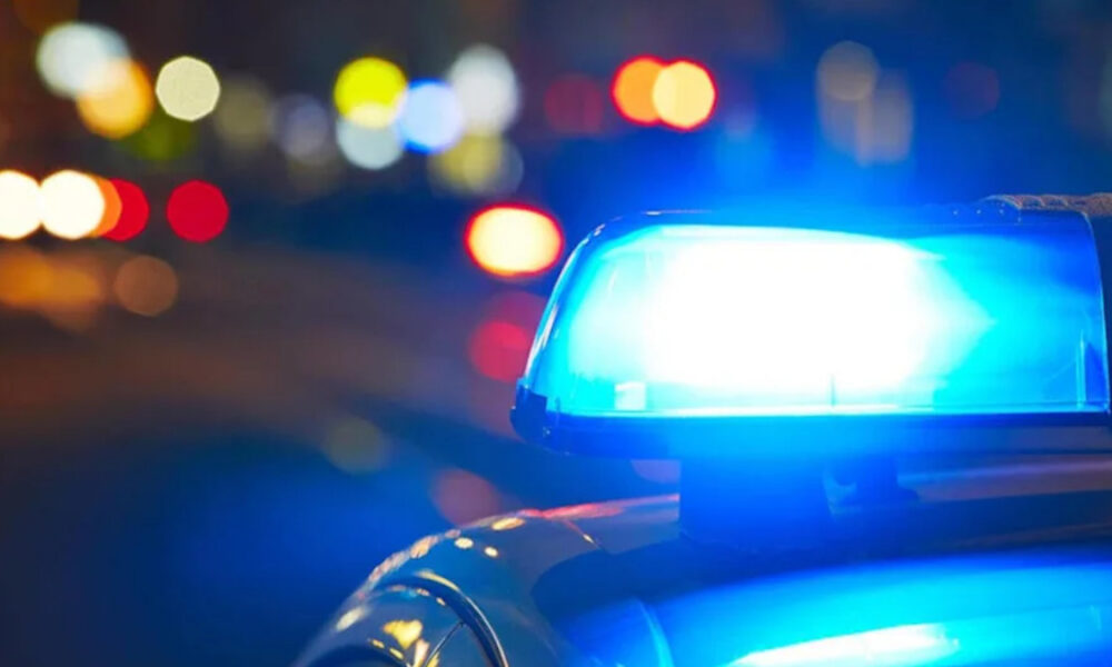 Blue police lights flashing on a patrol car at night with blurred city street bokeh in the background
