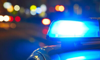 Blue police lights flashing on a patrol car at night with blurred city street bokeh in the background