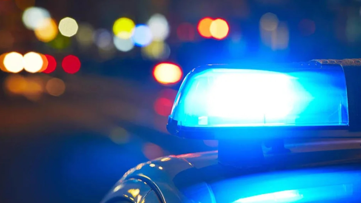 Blue police lights flashing on a patrol car at night with blurred city street bokeh in the background