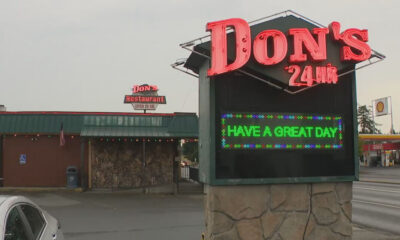Don's 24 Hr neon sign atop a stone kiosk; LED board reads 'HAVE A GREAT DAY' with a diner and string lights in the background.