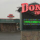 Don's 24 Hr neon sign atop a stone kiosk; LED board reads 'HAVE A GREAT DAY' with a diner and string lights in the background.