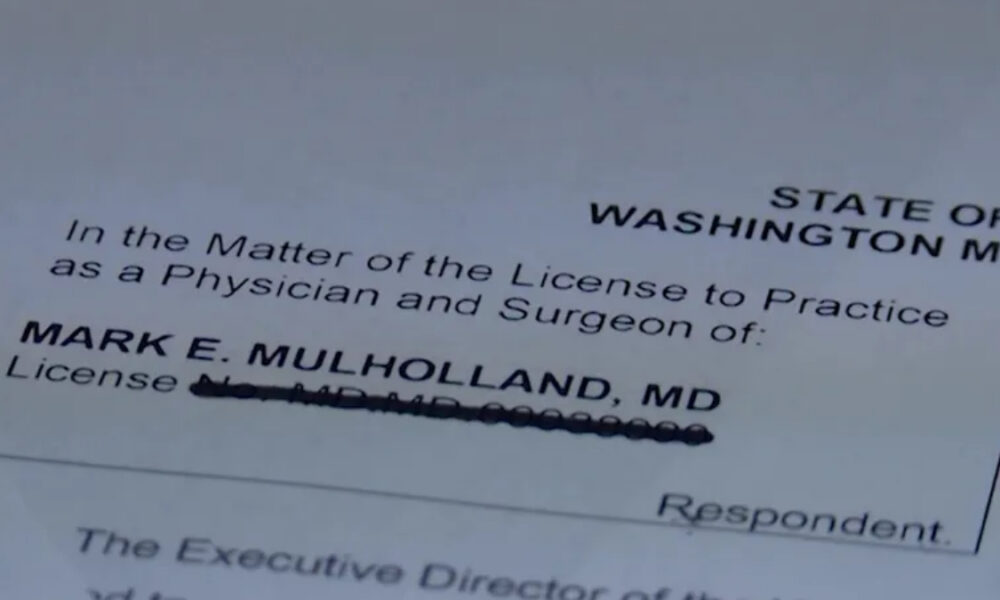 Close-up of a Washington medical license form showing the name Mark E. Mulholland, MD with the license line obscured/blurred.
