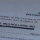 Close-up of a Washington medical license form showing the name Mark E. Mulholland, MD with the license line obscured/blurred.