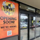 Storefront with a tall orange Spirit Halloween poster reading 'OPENING SOON!' and 'WE'RE HIRING,' including a QR code at the bottom.