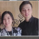 Two young adults, a woman and a man, smiling for a photo side by side indoors with a wooden backdrop behind them.