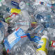 Pile of crushed plastic water bottles tangled in a recycling/trash heap, showing litter and waste cluttering a surface.