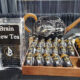 Display table featuring 'Brain New Tea' signs, with clear plastic stands and a wooden tray of small black bottles with gold caps labeled Brain New Tea Focus Shot.