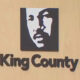Logo: stylized black-and-white face in a square above the text 'King County' on a wood background.