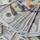 Pile of overlapping US $100 bills with Benjamin Franklin visible in the center.
