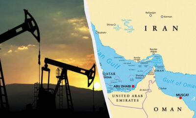 Silhouetted oil pump jacks at sunset beside a map highlighting Iran and the Persian Gulf region nearby neighboring countries.