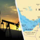 Silhouetted oil pump jacks at sunset beside a map highlighting Iran and the Persian Gulf region nearby neighboring countries.