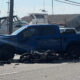 Blue Ford F-150 with front-end damage beside a downed motorcycle and debris on a harbor-side street.