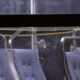 Bullet hole in a window with glass shatter and spray marks inside a vehicle with blue upholstered seats and metal frames.