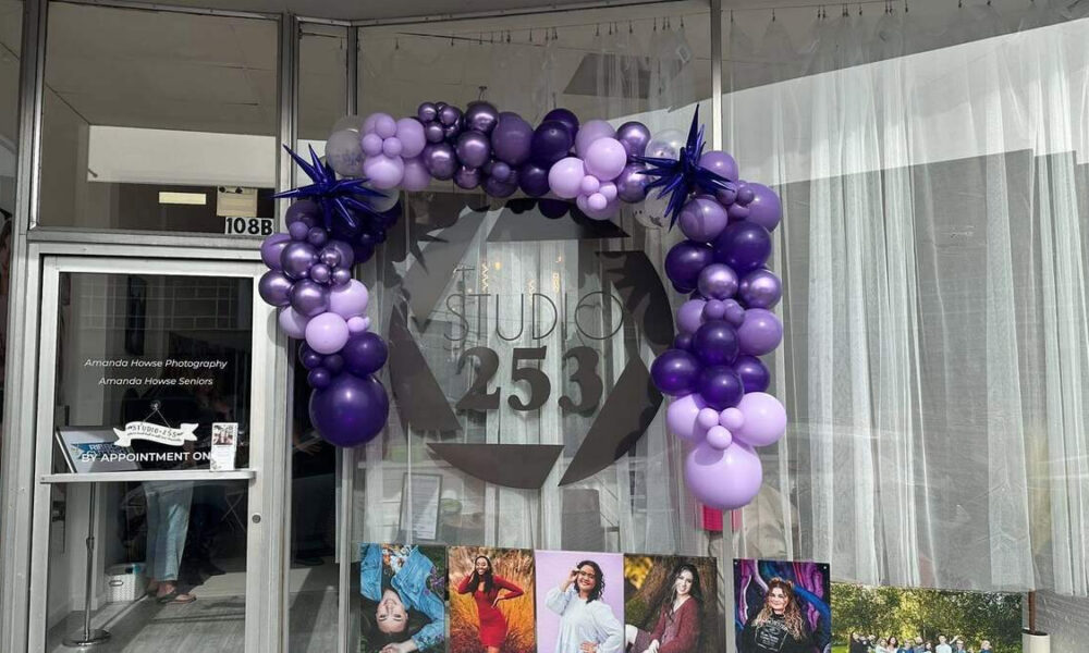 Purple balloon arch frames the glass door of Studio 253, a photography studio, with signage visible on the door and window signage reading Amanda Howse Photography.