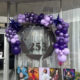 Purple balloon arch frames the glass door of Studio 253, a photography studio, with signage visible on the door and window signage reading Amanda Howse Photography.