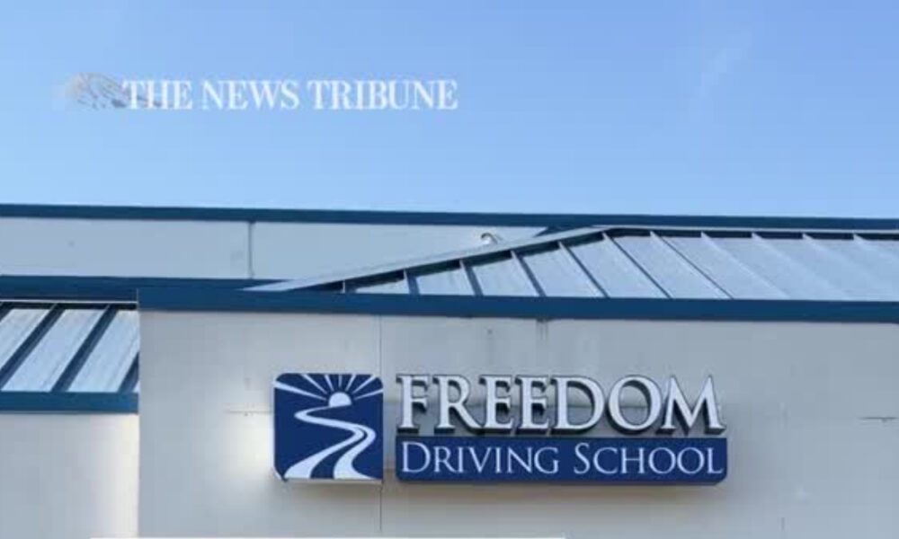 Exterior of a driving school building with a blue logo and sign reading 'FREEDOM Driving School'
