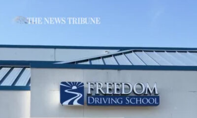 Exterior of a driving school building with a blue logo and sign reading 'FREEDOM Driving School'
