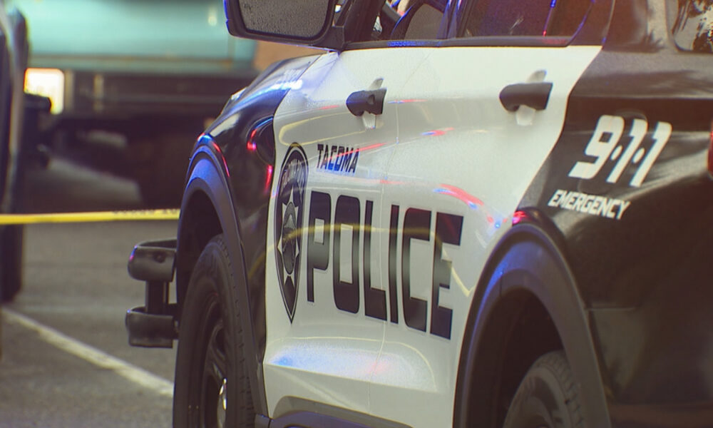 Police SUV with POLICE lettering and shield logo at a crime scene, yellow caution tape in the background.