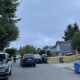 Residential street blocked off with yellow police tape; police vehicles and a few officers present in front of houses.