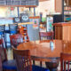 A cozy pizza shop interior with a round wooden table and six wooden chairs near a bar counter.