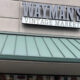 Storefront sign reading 'Wayman's Vintage Market' above a green metal awning on a gray brick façade, storefront visible below the awning.