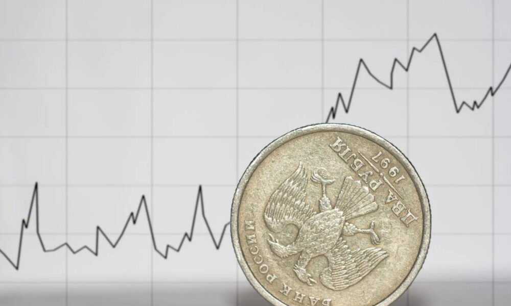 Close-up of a coin placed in front of a fluctuating line graph representing financial data.