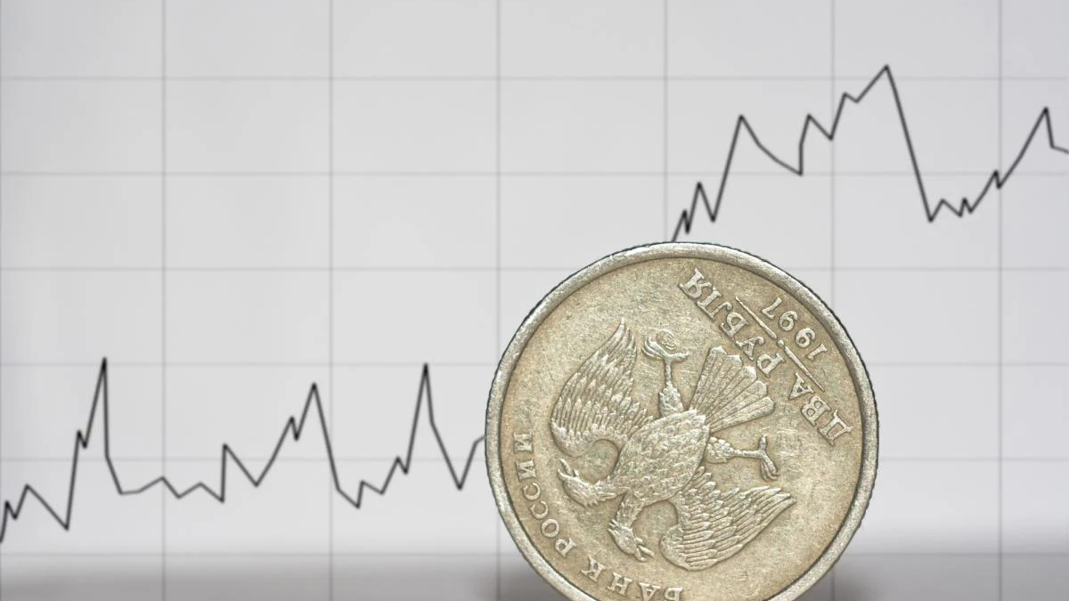 Close-up of a coin placed in front of a fluctuating line graph representing financial data.