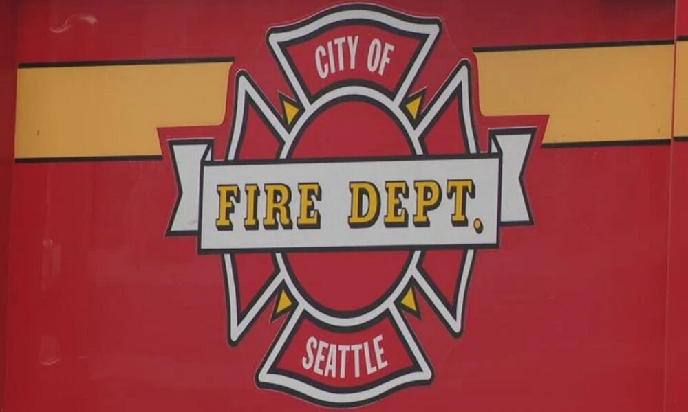 Emblem: City of Fire Dept Seattle badge on a red background with yellow accents and a white banner reading 'FIRE DEPT'.