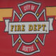 Emblem: City of Fire Dept Seattle badge on a red background with yellow accents and a white banner reading 'FIRE DEPT'.