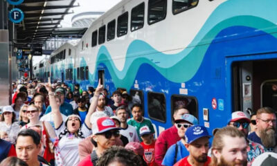 Crowded train platform with a blue and teal wave-patterned double-decker train and passengers boarding. Crowded train platform with a blue and teal wave-patterned double-decker train and passengers boarding.