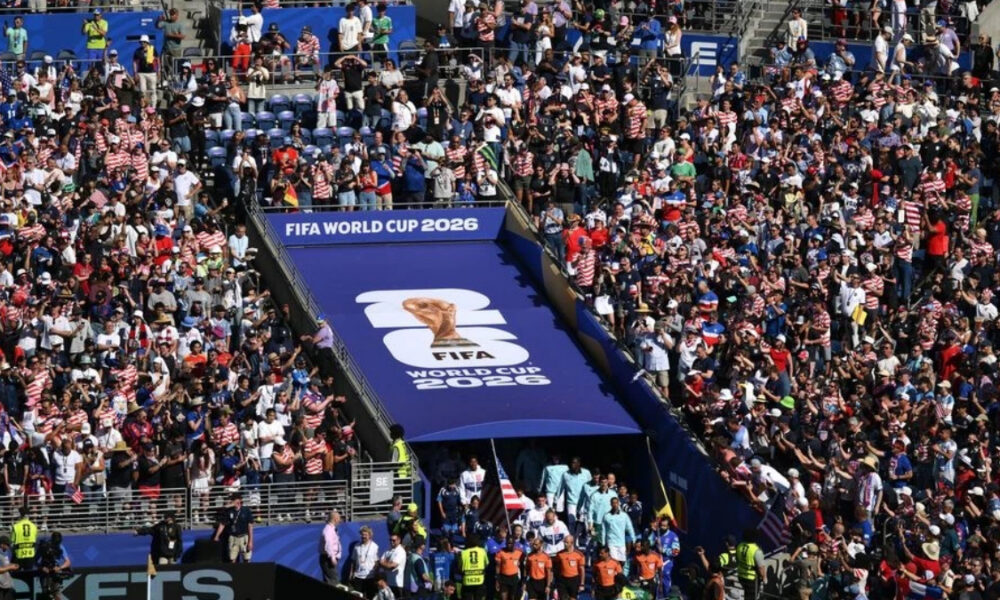 Large crowd gathered in a stadium for FIFA World Cup 2026, with a blue tunnel entrance and logo banner visible in the center