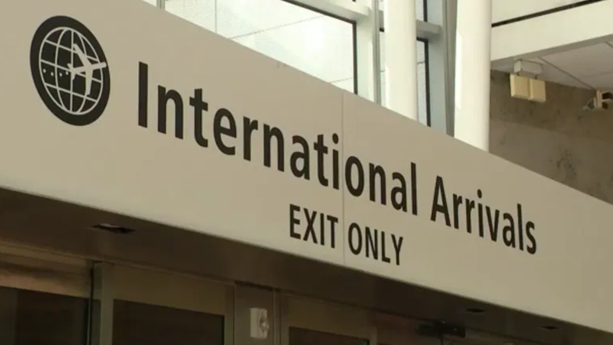 Airport sign reading International Arrivals, EXIT ONLY, with globe logo on the left.