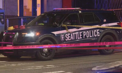 Seattle Police SUV at night with crime scene tape crossing the street and flashing lights nearby.
