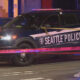 Seattle Police SUV at night with crime scene tape crossing the street and flashing lights nearby.